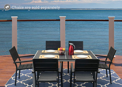 An outdoor dining scene featuring a rectangular composite wood dining table with a white frame, set against a stunning ocean view. The table is accompanied by black chairs with beige cushions, and there are place settings, a bowl of fruit, and a red pitcher on the table. Note: Chairs are sold separately. Rectangular Outdoor Dining Table with Ocean View (Chairs Sold Separately). rectangular outdoor dining table, composite wood table, white - framed table, outdoor chairs, ocean view dining