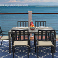 An outdoor dining scene featuring a rectangular composite wood dining table with a white frame, set against a stunning ocean view. The table is accompanied by black chairs with beige cushions, and there are place settings, a bowl of fruit, and a red pitcher on the table. Note: Chairs are sold separately. Rectangular Outdoor Dining Table with Ocean View (Chairs Sold Separately). rectangular outdoor dining table, composite wood table, white - framed table, outdoor chairs, ocean view dining