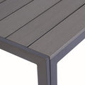 A close - up view of the corner of a rectangular composite wood dining table. The table features a sleek, modern design with a dark grey slatted tabletop and matching frame.Rectangular Composite Wood Dining Table: Close - up of the Corner. rectangular dining table, composite wood, dark grey tabletop, modern design, table corner
