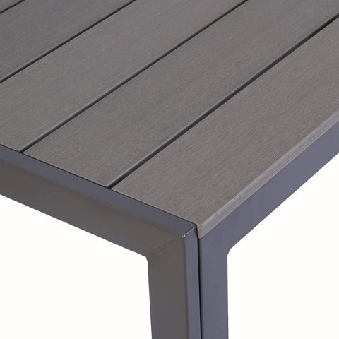 A close - up view of the corner of a rectangular composite wood dining table. The table features a sleek, modern design with a dark grey slatted tabletop and matching frame.Rectangular Composite Wood Dining Table: Close - up of the Corner. rectangular dining table, composite wood, dark grey tabletop, modern design, table corner
