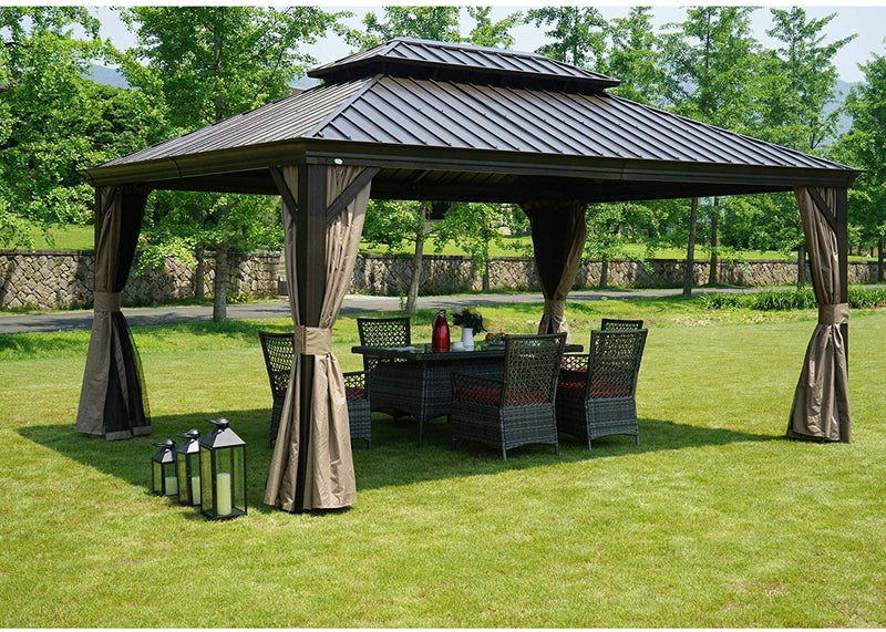 An outdoor hardtop gazebo with a dark - toned metal roof is set on a grassy lawn. The gazebo features earth - toned curtains that can be tied back, and underneath it, there is a wicker patio set with a table and chairs. Additionally, there are black lanterns placed on the grass nearby, enhancing the cozy outdoor ambiance.Cozy Outdoor Gazebo with Wicker Patio Set and Lanterns. outdoor gazebo, hardtop gazebo, wicker patio set, earth - toned curtains, black lanterns