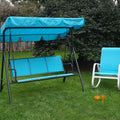 A blue-colored outdoor swing chair with a matching canopy is set on a lush green lawn, accompanied by a gray-hued rocking chair with patterned cushions. The swing chair, featuring the brand "Kozyard," provides a cozy spot for relaxation in a garden setting, surrounded by greenery and a wooden fence in the background. Blue Kozyard Swing Chair: A Relaxing Outdoor Retreat.blue swing chair, Kozyard swing, outdoor seating, garden swing, rocking chair