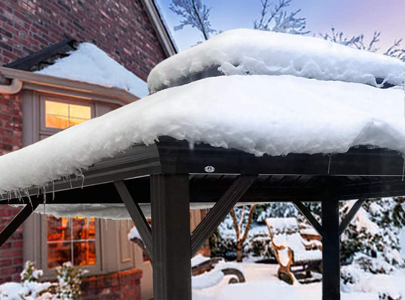 An outdoor gazebo covered in a thick layer of snow, with icicles hanging from the edge of its roof. The scene is set in a winter environment with a brick house in the background, partially illuminated windows suggesting warmth inside. Snow - laden bushes and trees add to the wintry atmosphere.Winter - Coated Outdoor Gazebo: A Snowy Retreat. outdoor gazebo, winter scene, snow - covered, icicles, brick house background.