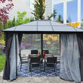 A stylish gazebo with a modern, dark - colored roof stands on a patio adjacent to a home. It is equipped with dark privacy curtains and sheer mesh panels, providing both seclusion and protection from bugs. The gazebo houses a black outdoor dining set, and the area is enhanced by the lush plants and colorful blooms in the background. Modern Outdoor Gazebo: Ideal for Garden Dining. Stylish Gazebo with Mesh and Curtains for Outdoor Relaxation. outdoor gazebo, garden gazebo, mesh netting, privacy curtains