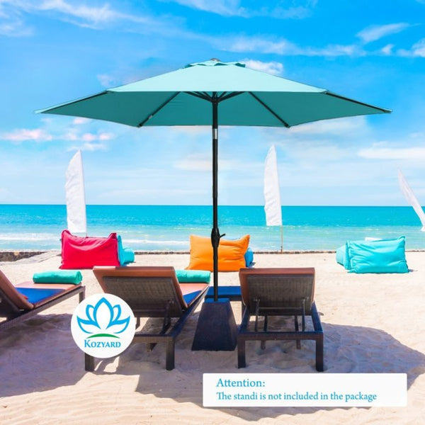 A blue outdoor beach umbrella set on a sandy beach with a stunning blue - sea backdrop. Beneath the umbrella are lounge chairs, colorful bean bags, and blue cushions. A logo for "KOZYARD" is visible, and a notice states that the stand is not included in the package. KOZYARD Outdoor Beach Umbrella for Relaxing by the Sea. outdoor beach umbrella, KOZYARD, beach lounge, outdoor relaxation, umbrella stand not included