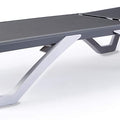 A modern outdoor lounge bed with a sleek design. It has a flat, gray - colored surface and is supported by a white, angular frame. The adjustable backrest mechanism is visible at the rear. Sleek Modern Outdoor Lounge Bed. outdoor lounge bed, modern design, adjustable backrest, gray surface, white frame.