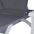 A close - up view of a modern outdoor lounge bed with a gray breathable Textilene fabric. The lounge bed has a sleek, contemporary frame in light grey and white, and is positioned next to a white side table with a glass of orange juice on it. Contemporary Outdoor Lounge Bed with Breathable Fabric. outdoor lounge bed, breathable Textilene fabric, modern design, side table.