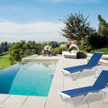 Two modern outdoor blue lounge beds with sleek grey and white frames are placed beside a swimming pool in a luxurious outdoor setting. The lounge beds have adjustable backrests.The background features lush greenery and a scenic view of a golf course. Modern Outdoor Lounge Beds by the Pool. outdoor lounge beds, swimming pool furniture, adjustable backrest, modern design, luxury outdoor setting. 