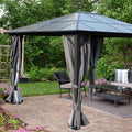 A stylish outdoor gazebo with a dark - colored, geometric - patterned roof stands on a paved patio. The gazebo is adorned with elegant grey curtains that can be tied back, and it houses comfortable outdoor furniture including a sofa, chairs, and a coffee table. Surrounding the gazebo are lush green plants and vibrant flowers, creating a serene garden setting. Elegant Outdoor Gazebo: Perfect for Garden Relaxation. Stylish Gazebo in a Lush Garden Setting. outdoor gazebo, garden gazebo, grey curtains, patio fu