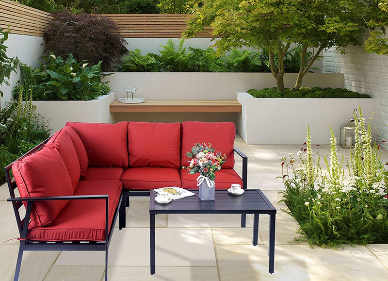 A vibrant outdoor seating set featuring a striking red - cushioned sectional sofa paired with a sleek black coffee table. The setup is placed on a light - colored tiled patio, surrounded by lush greenery and elegant garden elements, creating an inviting and stylish outdoor lounge area.Stylish Red Outdoor Sofa Set for Patio Lounging. outdoor sofa set, red cushions, black coffee table, patio furniture, garden seating, outdoor lounge area
