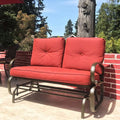 A vibrant red - cushioned glider chair placed on an outdoor patio. The chair features a sturdy metal frame with curved armrests, providing a comfortable spot for relaxation. The background includes greenery and a brick wall, enhancing the inviting outdoor atmosphere. Red - Cushioned Glider Chair for Outdoor Relaxation. red - cushioned glider chair, outdoor patio furniture, metal - framed chair, curved armrests, relaxation.
