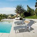 Two gray foldable lounge chairs placed beside a swimming pool in a luxurious outdoor setting. The chairs feature built-in cup holders, perfect for relaxing by the pool. The background includes lush greenery and additional outdoor furniture, enhancing the serene and leisurely atmosphere. gray foldable lounge chairs, poolside lounge chairs, outdoor relaxation, built-in cup holders.