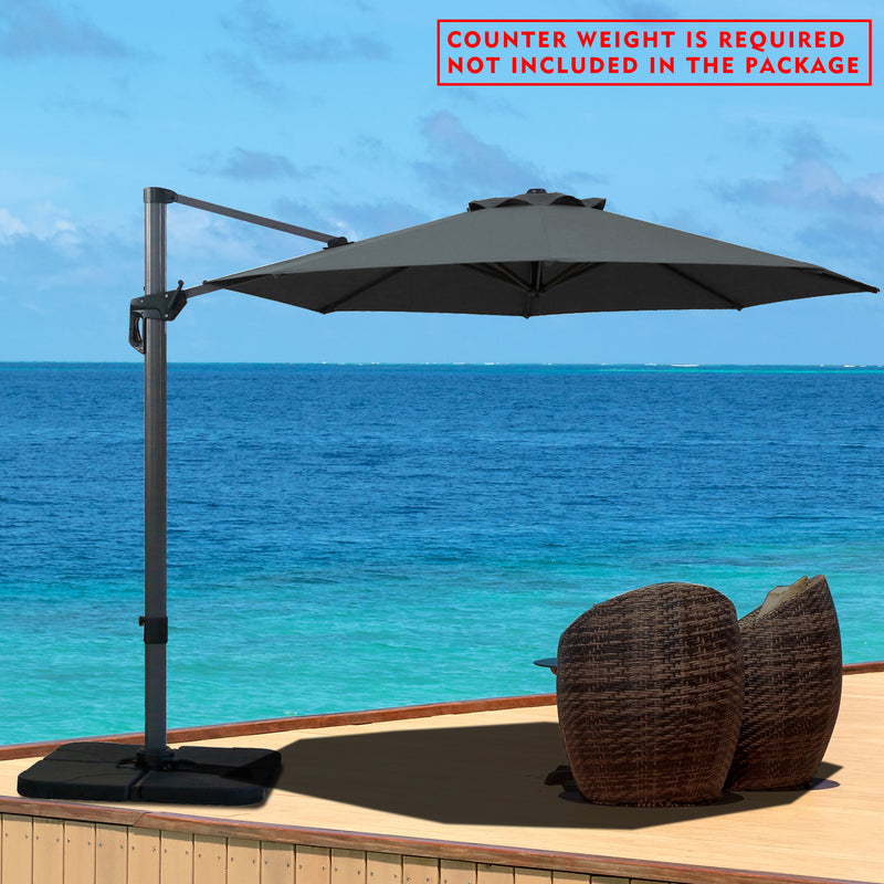 A gray cantilever patio umbrella set up on a wooden deck overlooking the ocean. Note: Counter weight is required and not included in the package.
Outdoor offset umbrella providing shade near wicker chairs by the seaside. Counter weight needed, not part of the package. Seaside Cantilever Umbrella: Counter Weight Not Included. Ocean - View Patio Umbrella: Counter Weight Required. cantilever umbrella, patio umbrella, outdoor umbrella, seaside umbrella, counter weight, wicker chairs, ocean - view