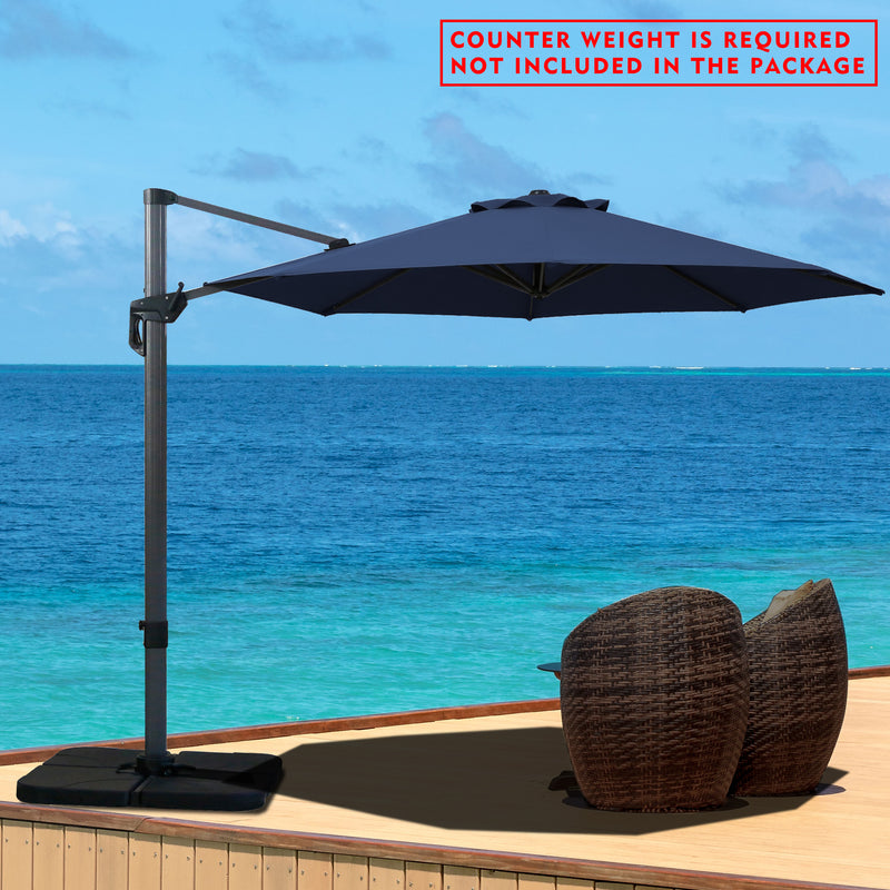 A navy blue cantilever patio umbrella set up on a wooden deck overlooking the ocean. Note: Counter weight is required and not included in the package.
Outdoor offset umbrella providing shade near wicker chairs by the seaside. Counter weight needed, not part of the package. Seaside Cantilever Umbrella: Counter Weight Not Included. Ocean - View Patio Umbrella: Counter Weight Required. cantilever umbrella, patio umbrella, outdoor umbrella, seaside umbrella, counter weight, wicker chairs, ocean - view