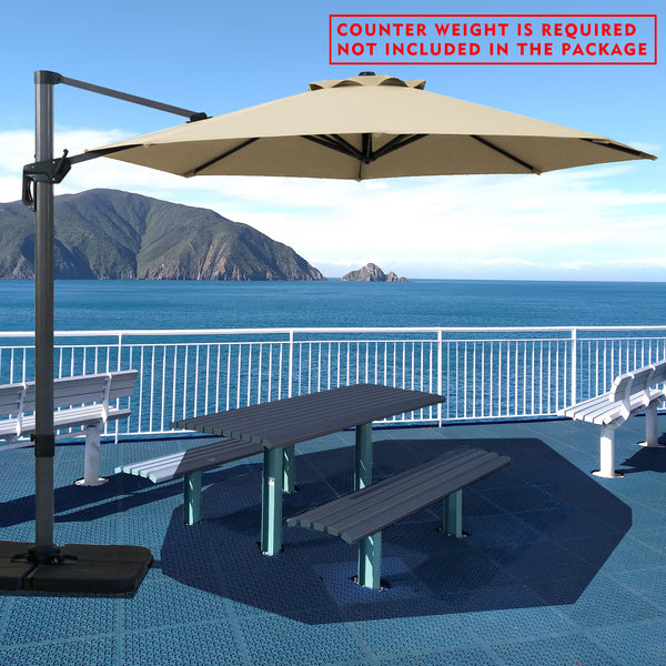 Beige cantilever patio umbrella providing shade over a picnic table by the seaside. Note: Counter weight is required and not included in the package. Outdoor offset umbrella in a coastal setting. It shades an outdoor table, and a counter weight is needed but not part of the package. Seaside Patio Umbrella: Counter Weight Not Included. Cantilever Umbrella for Outdoor Use: Counter Weight Required. cantilever umbrella, patio umbrella, outdoor umbrella, counter weight, umbrella shade