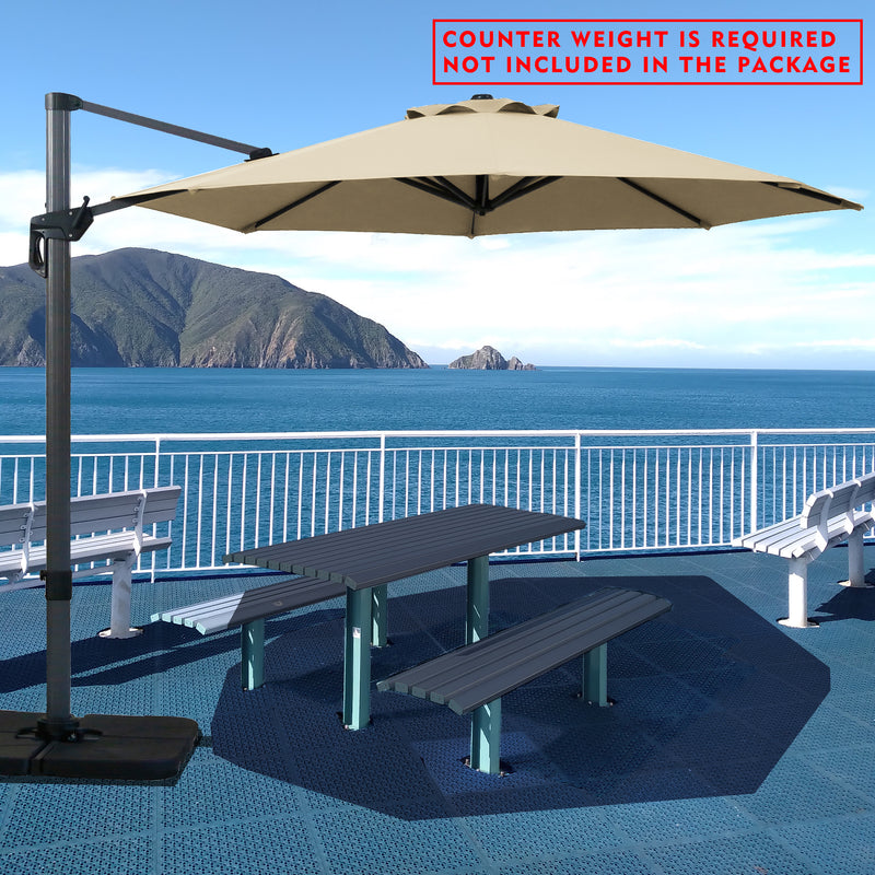 Beige cantilever patio umbrella providing shade over a picnic table by the seaside. Note: Counter weight is required and not included in the package. Outdoor offset umbrella in a coastal setting. It shades an outdoor table, and a counter weight is needed but not part of the package. Seaside Patio Umbrella: Counter Weight Not Included. Cantilever Umbrella for Outdoor Use: Counter Weight Required. cantilever umbrella, patio umbrella, outdoor umbrella, counter weight, umbrella shade