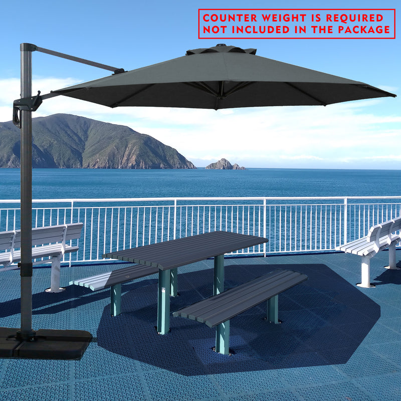 Gray cantilever patio umbrella providing shade over a picnic table by the seaside. Note: Counter weight is required and not included in the package. Outdoor offset umbrella in a coastal setting. It shades an outdoor table, and a counter weight is needed but not part of the package. Seaside Patio Umbrella: Counter Weight Not Included. Cantilever Umbrella for Outdoor Use: Counter Weight Required. cantilever umbrella, patio umbrella, outdoor umbrella, counter weight, umbrella shade