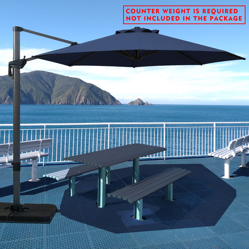 Navy blue cantilever patio umbrella providing shade over a picnic table by the seaside. Note: Counter weight is required and not included in the package. Outdoor offset umbrella in a coastal setting. It shades an outdoor table, and a counter weight is needed but not part of the package. Seaside Patio Umbrella: Counter Weight Not Included. Cantilever Umbrella for Outdoor Use: Counter Weight Required. cantilever umbrella, patio umbrella, outdoor umbrella, counter weight, umbrella shade