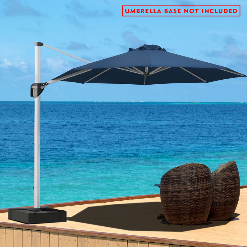 A navy blue- colored cantilever patio umbrella stands on a wooden deck overlooking a stunning blue ocean. The umbrella is positioned to provide shade over a pair of wicker chairs. A red notice at the top states "UMBRELLA BASE NOT INCLUDED". The serene seascape in the background enhances the relaxing outdoor setting.Navy blue Cantilever Patio Umbrella by the Sea: Base Not Included.cantilever patio umbrella, offset umbrella, navy blue umbrella, umbrella base not included, seaside patio, wicker chairs.
