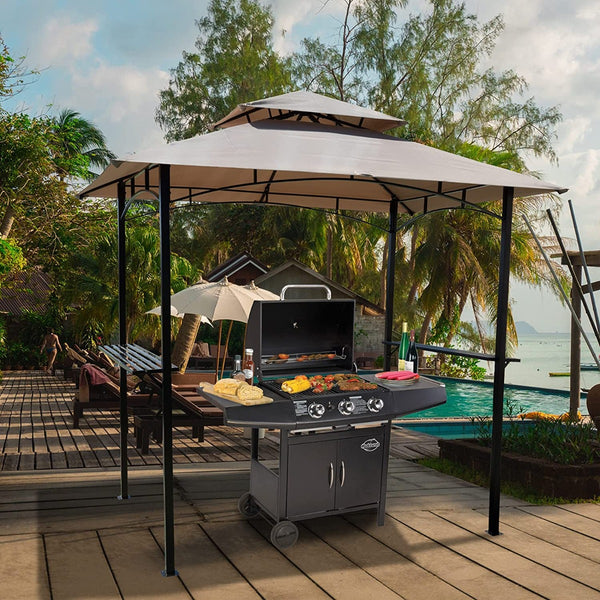 An outdoor barbecue gazebo with a beige canopy provides shade over a modern grill loaded with various foods being cooked. The scene is set by a poolside with palm trees, lounge chairs, and a scenic view of the water in the background, creating a perfect spot for outdoor cooking and relaxation. Beige - Canopied Outdoor Barbecue Gazebo by the Poolside. outdoor barbecue gazebo, beige canopy, grill, poolside, outdoor cooking
